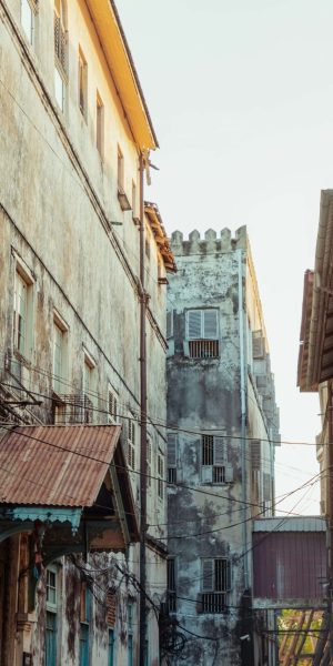 house A narrow street lined with old buildings, featuring a prominent blue door at the end.